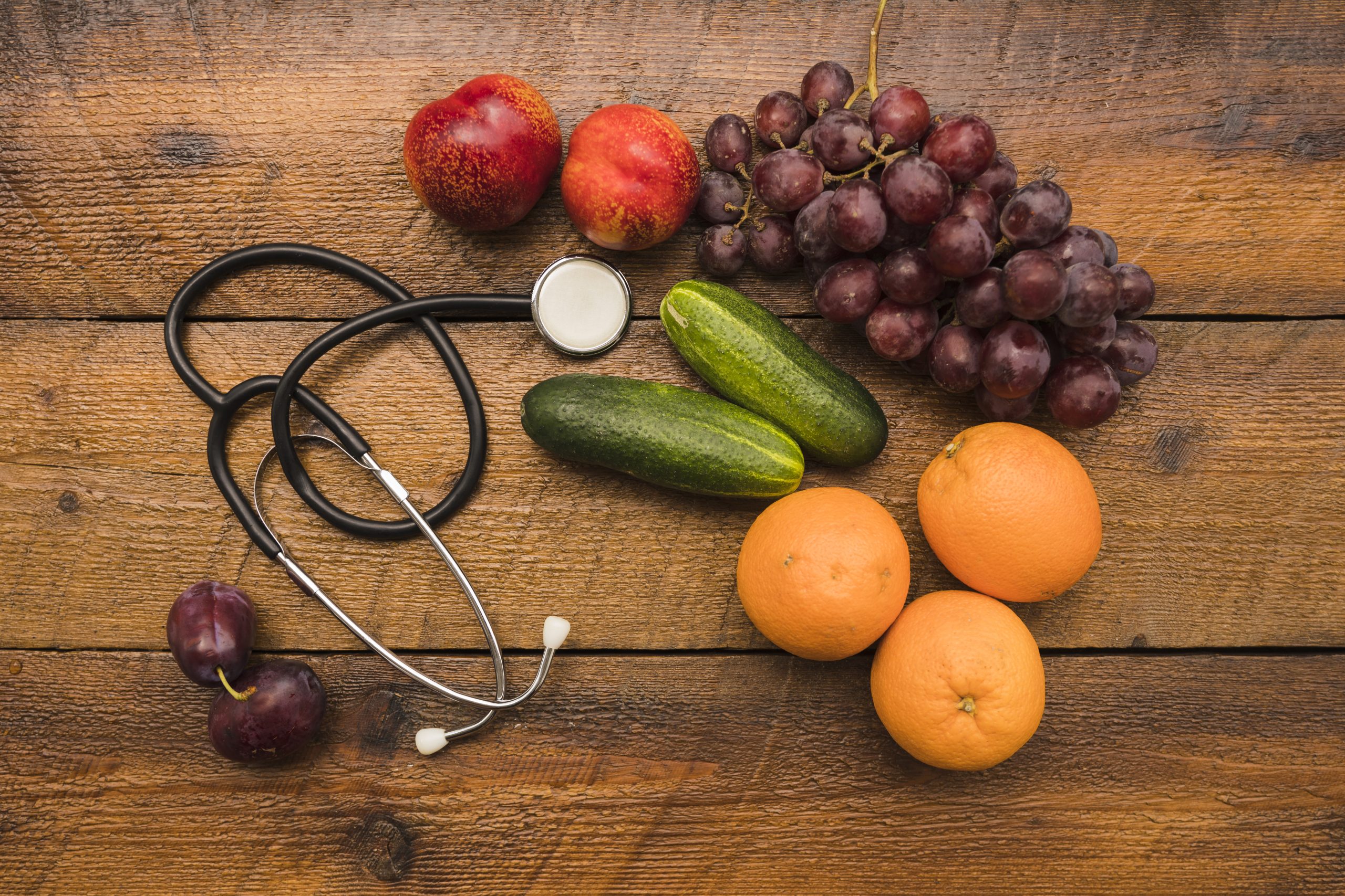 elevated-view-healthy-fruits-with-stethoscope-wooden-background